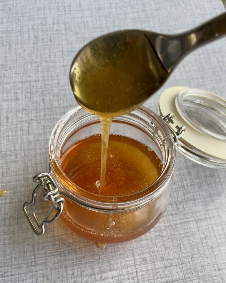 Et glas gylden hot honey med et let strejf af chili, klar til brug som en sød og stærk topping.