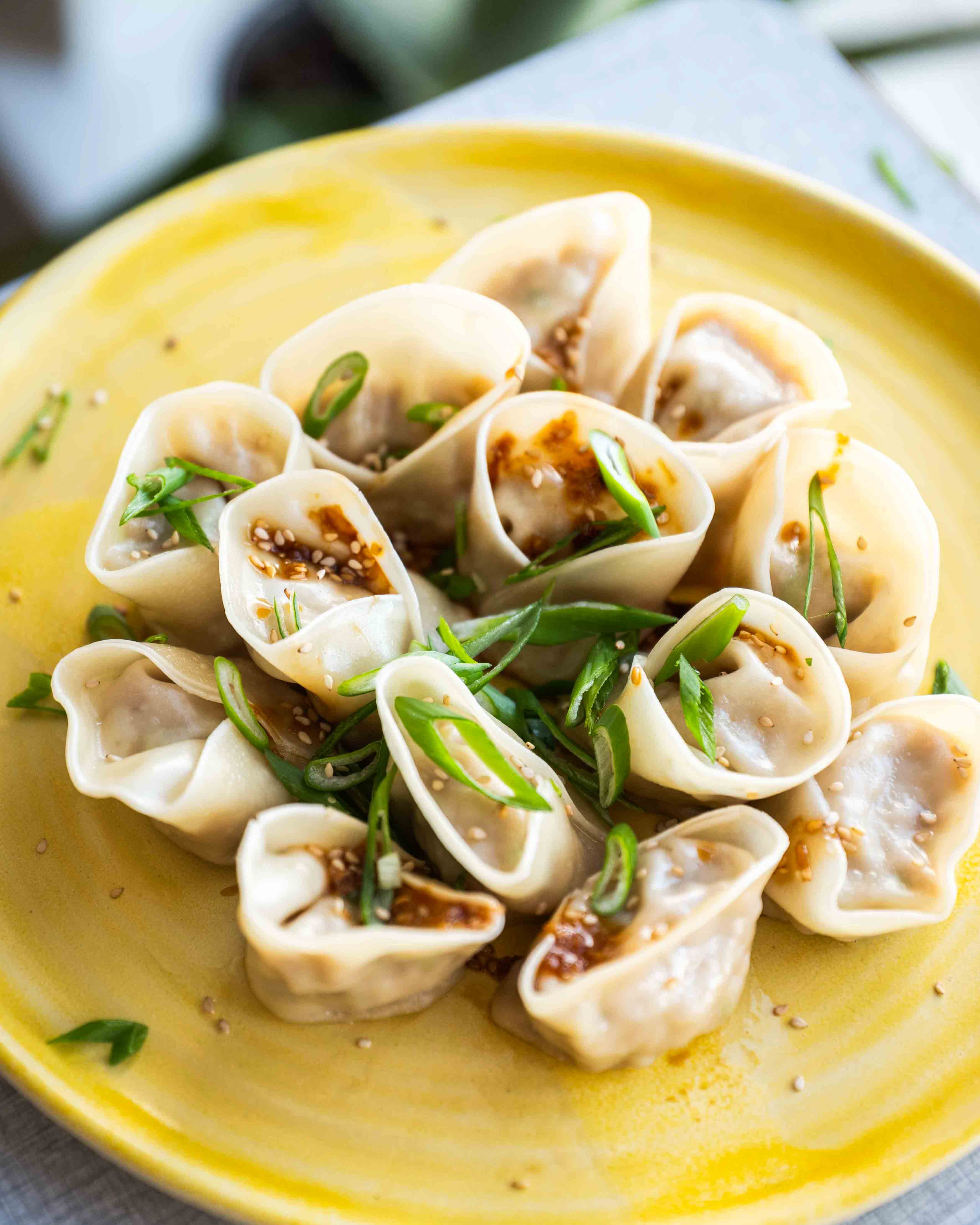 Et nærbillede af frisklavede dumplings med kylling, toppet med forårsløg og sesamfrø