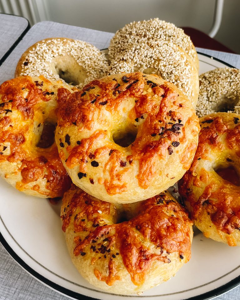 Alt-tekst til billede: Hjemmelavede bagels toppet med sesamfrø, krydderier, cheddarost og chiliflager, klar til servering.