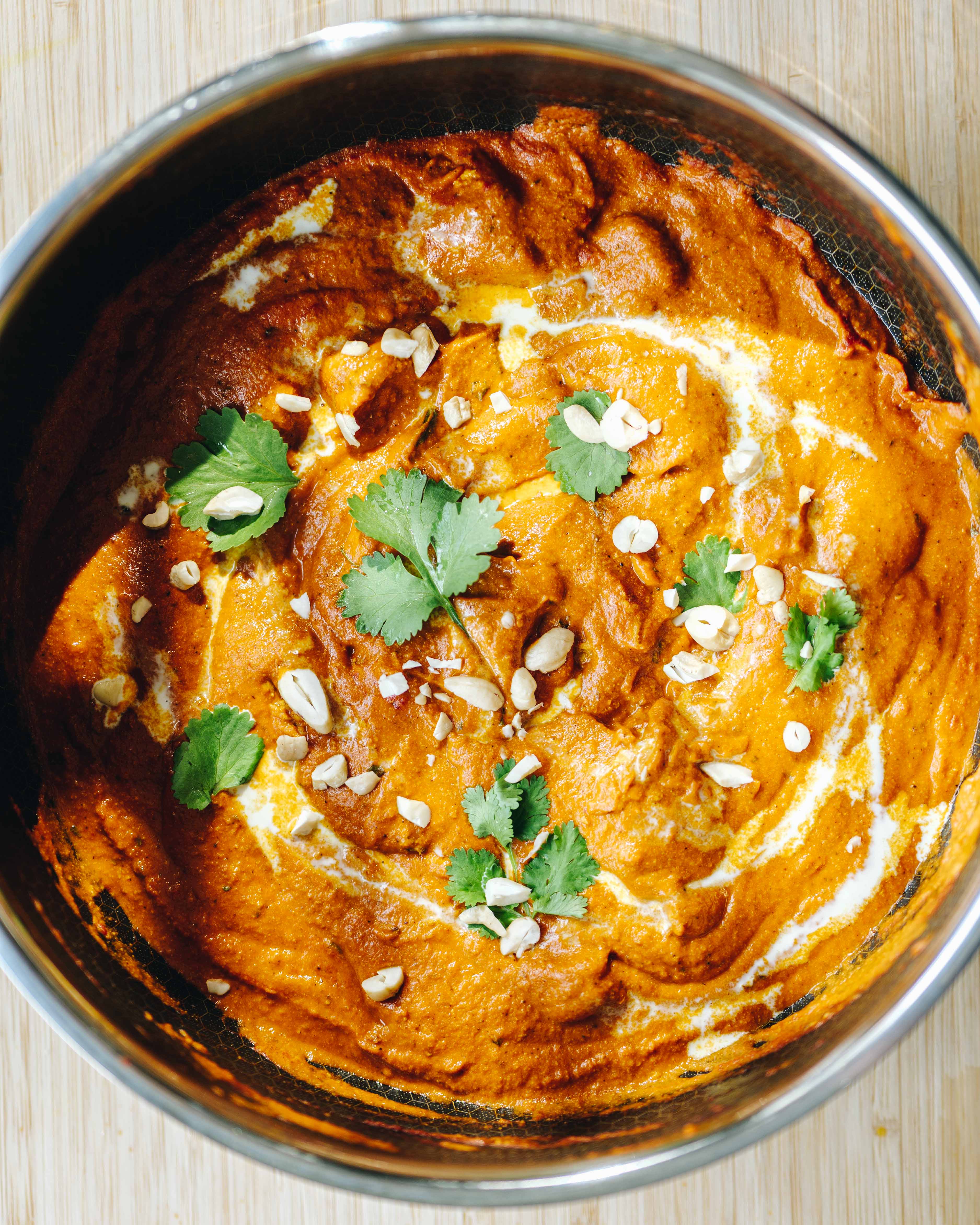 Cremet butter chicken med grillede kyllingestykker i tomatsauce, toppet med koriander og serveret med naan