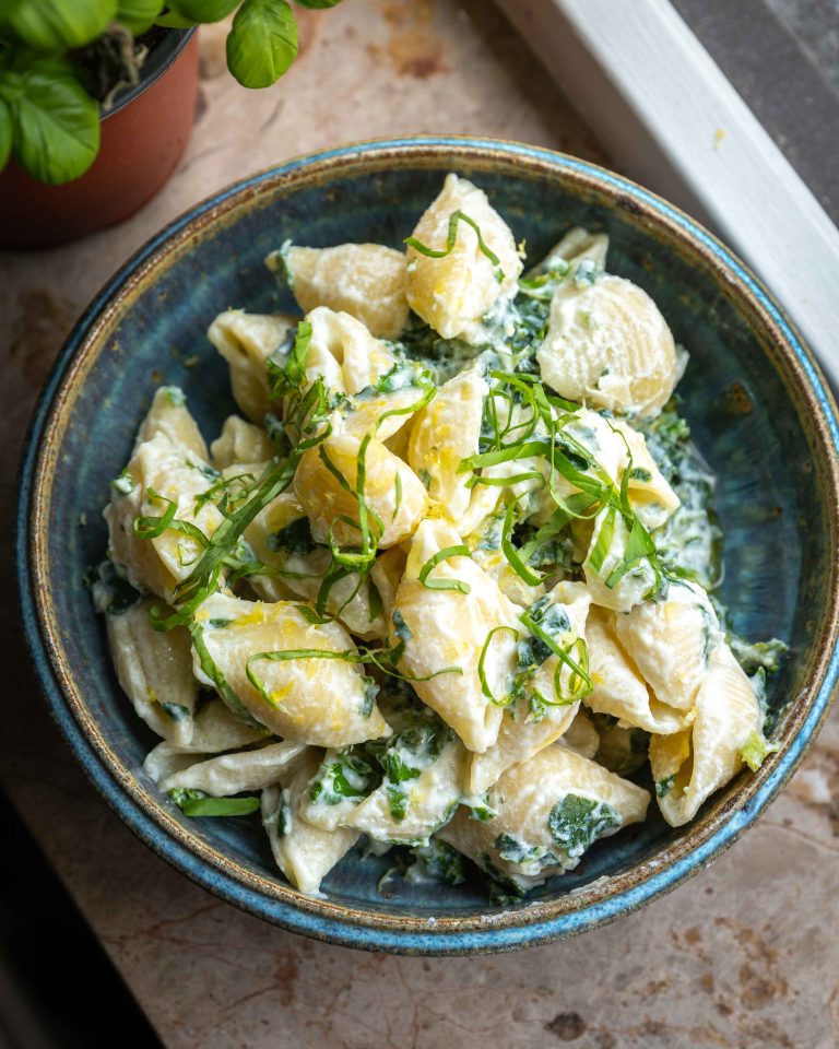 Cremet pasta med ricotta, citron og grønkål toppet med frisk basilikum i en skål